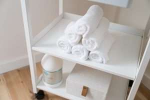 Hot towels and organic massage lotion on a cart in a massage therapy room in Asheville, NC