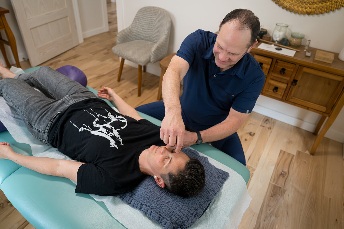 Chad Johnson, L.Ac., assessing a patient's trapezius at Asheville Orthopedic Acupuncture